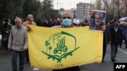 A protester holds the flag of the Afghan Shiite group Liwa Fatemiyoun, a militia formed in 2014 to fight in Syria on the side of the regime, during a protest in support of Yemen and Palestinians, in Tehran, Jan. 12, 2024.