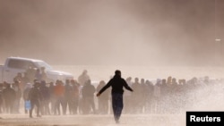 2023年4月25日，从墨西哥华雷斯城看到的移民在越过布拉沃河后，站在边境墙附近，打算向美国边境巡逻队特工自首。（路透社照片）