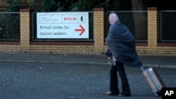 A woman with a suitcase leaves the central registration center for asylum seekers in Berlin, Germany, Sept. 26, 2023.