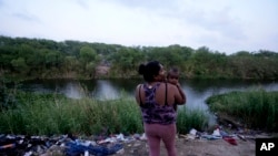 Honduran migrant Maria Karina Balladares holds her son on the Mexican side of the Rio Grande where other migrants have crossed over into the U.S. to turn themselves to immigration authorities, in Matamoros, Mexico, May 11, 2023.