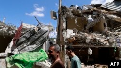 Palestinians walk past a damaged house after a raid by Israeli forces in the Nur Shams camp for Palestinian refugees in the occupied West Bank on April 21, 2024.