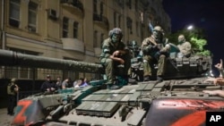 FILE - Members of the Wagner Group military company sit atop of a tank on a street in Rostov-on-Don, Russia, June 24, 2023, prior to leaving an area at the headquarters of the Southern Military District.