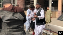 An injured man is led out of a building after a bomb blast, in Mazar-e-Sharif, the capital of northern Afghanistan's Balkh province, March 11, 2023.