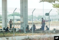 Myanmar soldiers are seen on the Myanmar side of a bridge across the Moei River linking to the district of Mae Sot in Thailand's Tak province on April 11, 2024.