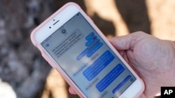 FILE - In this Feb. 15, 2018, file photo, a woman shows text messages she received from her son the day before, during a community vigil in Parkland, Fla.