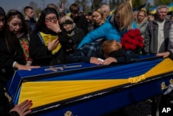 Relatives mourn next to the coffin of Ukrainian serviceman Andrii Vorobiov at the Kryvyi Rih cemetery in eastern Ukraine, April 24, 2023.