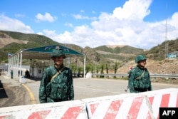 FILE - Men guard an Azerbaijani checkpoint set up at the entry of the Lachin corridor, the Armenian-populated breakaway Nagorno-Karabakh region's only land link with Armenia, by a bridge across the Hakari river, on May 2, 2023.