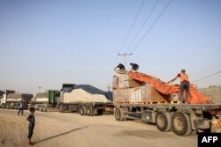 People unload humanitarian aid on a convoy of lorries entering the Gaza Strip from Egypt via the Rafah border crossing, Oct. 21, 2023.
