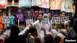 People buy dresses from a shop in a market ahead of Eid al-Fitr celebrations in Karachi, Pakistan, April 19, 2023.