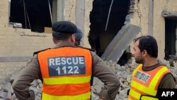 Rescuers stand at the site of an attack after militants rammed an explosive-laden vehicle into a Pakistan military base, in the town of Daraban of Dera Ismail Khan district, in Khyber Pakhtunkhwa province, on Dec. 12, 2023.