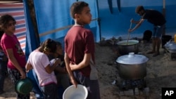Palestinian children wait for a food distribution in a displaced tent camp, in Khan Younis, southern Gaza Strip, Oct. 25, 2023.