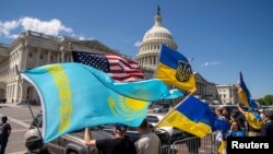 Pengunjuk rasa membawa bendera Kazakstan, AS, dan Ukraina di luar Gedung Kongres AS setelah voting undang-undang yang memberikan bantuan senilai $95 miliar kepada Ukraina, Israel, dan Taiwan. (Foto: REUTERS/Ken Cedeno)