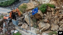 Machinery is used to remove rocks from a road in the aftermath of storms in Shijiaying, Fangshan district, on the outskirts of Beijing, Aug. 6, 2023. Multiple people have been killed in recent flooding in China's capital. (Xinhua via AP)