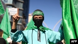 Demonstrators carry flags of the Palestinian Hamas group during an anti-Israel rally in Hebron, in the occupied West Bank, Dec. 15, 2023.