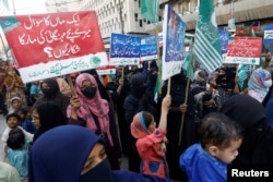 Women along with their children carry placards as they take part in a protest against price increases, in Karachi, Pakistan, Feb. 15, 2023.