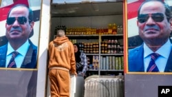 A man buys groceries at a government sponsored shop decorated with with Egyptian President Abdel Fattah el-Sissi posters in Cairo, Egypt, Sunday, Feb. 26, 2023. (AP Photo/Amr Nabil)