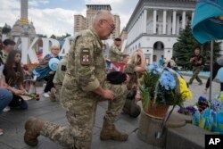 People lay flowers at a spontaneous memorial to soldiers killed in the war with Russia in Independence Square in Kyiv, Ukraine, May 23, 2024.