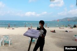 FILE - A waiter works in a beach with a few Western tourists, which is usually full of Chinese tourists, amid fear of coronavirus in Phuket, Thailand, March 10, 2020.