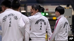 North Korean women wearing track suits with the North Korean flag hold hands as they line up to check in for a flight to Astana, Kazakhstan, at the Capital Airport in Beijing, Aug. 18, 2023. 