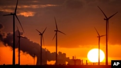 FILE -- Steam rises from the coal-fired power plant near wind turbines Niederaussem, Germany, as the sun rises Nov. 2, 2022.