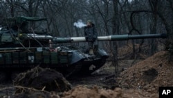 A Ukrainian serviceman smokes a cigarette while standing on top of a tank near Bakhmut, Ukraine, March 8, 2023. 