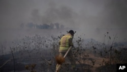 A firefighter works to extinguish a fire following an attack from Lebanese Hezbollah group in the Israeli-controlled Golan Heights, July 4, 2024. 