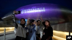 Dongdaemun Design Plaza is illuminated in purple as fans take a selfie in Seoul, South Korea, June 12, 2023. Several landmarks in South Korea's capital will be lit in purple on Monday as the country celebrates the 10th anniversary of K-pop band BTS, a source of national pride.