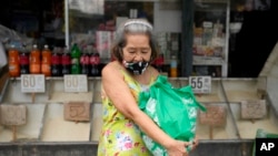 A woman carries a bag of rice from a store in Quezon city, Philippines, on Monday, Aug. 14, 2023. Countries worldwide are scrambling to secure rice after a partial ban on exports by India cut supplies by roughly a fifth.