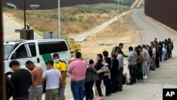 FILE - Migrants seeking asylum line up while waiting to be processed after crossing the border in San Diego, California, June 5, 2024. 