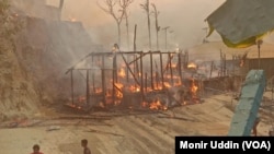 A bamboo skeleton of a shanty stands still as fire keeps burning the tarpaulin in Balukhali refugee camp in Bangladesh, March 5, 2023.