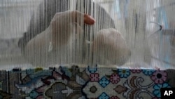 An Iranian woman weaves a carpet at a workshop in the city of Kashan, Iran, about 245 kilometers south of the capital, Tehran, April 30, 2024.