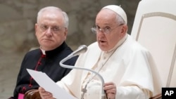 Pope Francis flanked by Father Leonardo Sapienza, left, delivers his speech during his weekly general audience in the Paul VI hall at The Vatican, Aug. 30, 2023.