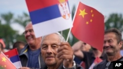 A man waves Chinese and Serbian flags as he waits for the arrival of Chinese President Xi Jinping and his Serbian counterpart, Aleksandar Vucic, outside the Serbia Palace in Belgrade, May 8, 2024.