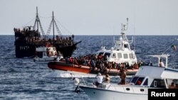 FILE - An Italian Coast Guard vessel carrying migrants rescued at sea passes between tourist boats, on Sicilian island of Lampedusa, Italy, Sept. 18, 2023.