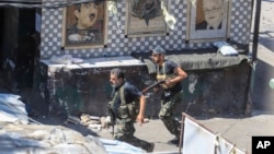 FILE - Members of the Palestinian Fatah group run to take position during a third day of clashes that erupted with Islamist factions in the Palestinian refugee camp of Ein el-Hilweh near the southern port city of Sidon, Lebanon, on July 31, 2023. 