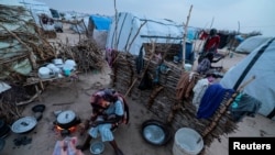 FILE - Sudanese women, who fled the conflict in Sudan's Darfur region, cook at their makeshift shelters in Adre, Chad Aug. 3, 2023.