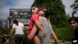 Venezuela migrant Naiber Zerpa holds her son, Mathias Marquez, as they arrive at a temporary camp after walking across the Darien Gap from Colombia, in Lajas Blancas, Panama, June 28, 2024.