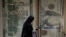 FILE - An Egyptian woman walks past an exchange office in Cairo, Egypt, March 6, 2024. 