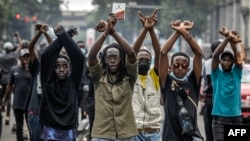 FILE - Protesters make signs with their arms in front of Kenya police officers during a demonstration against tax hikes as Members of the Parliament debate the Finance Bill 2024 in downtown Nairobi, June 18, 2024. 