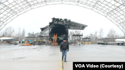 Олександр Галуненко, перший пілот, який здійснив політ на "Мрії", біля хвостової частини літака в аеропорту "Антонов" у Гостомелі. Лютий 2024. VOA Video