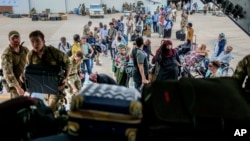 In this photo provided by the UK Ministry of Defence, British nationals prepare to be evacuated onto a RAF aircraft at Wadi Seidna Air Base, in Sudan, April 27, 2023.