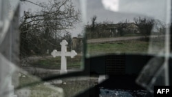 FILE - A cross is reflected on a broken window of a village church in Ukraine's southern Kherson region, amid Russia's invasion of its neighbor, Dec. 30, 2022.