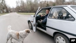 Yevgeny Markevich, a 85-year-old former teacher, speaks to his dog as he prepares to drive at the Chernobyl exclusion zone, Ukraine, April 14, 2021.