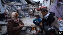 Members of a family break their fast during the Muslim holy month of Ramadan outside their home destroyed by the Israeli airstrikes, in Rafah, southern Gaza Strip, March 18, 2024.