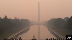 With the Washington Monument in the background and a thick layer of smoke, Marine Corps honor color guard rehearse, June 8, 2023, in Washington.