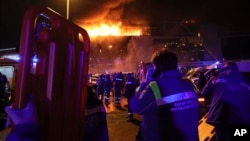 Seorang petugas medis berdiri di dekat ambulans yang diparkir di luar gedung Balai Kota Crocus yang terbakar di tepi barat Moskow, Rusia, Jumat, 22 Maret 2024. (Foto: AP)