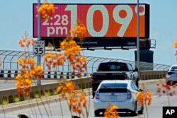 FILE - A digital billboard displays an unofficial temperature on July 17, 2023, in downtown Phoenix.