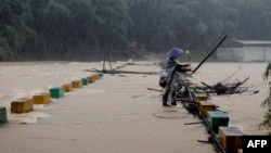 A villager clears tree branches stuck on a bridge in the rain at a flooded area in Liuzhou, in southwestern China's Guangxi province, June 13, 2024.