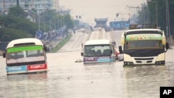 Public minibuses are caught in the flooded streets of Dar es Salaam, Tanzania, April 25, 2024. Flooding in Tanzania caused by weeks of heavy rain has killed 155 people and affected more than 200,000 others, the prime minister said Thursday.