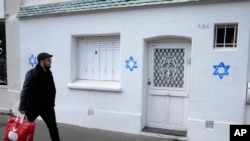 FILE - A man walks by Stars of David tagged on a wall in Paris, on Oct. 31, 2023.